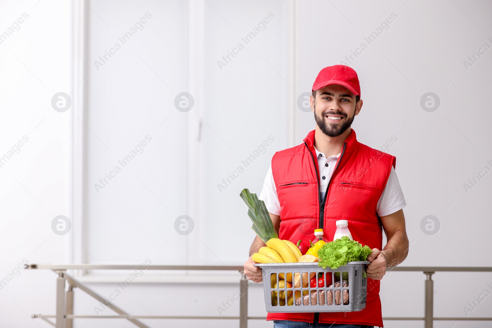 Photo of Man holding basket with fresh products indoors, space for text. Food delivery service