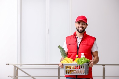 Photo of Man holding basket with fresh products indoors, space for text. Food delivery service