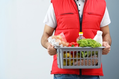 Photo of Man holding basket with fresh products indoors, closeup. Food delivery service