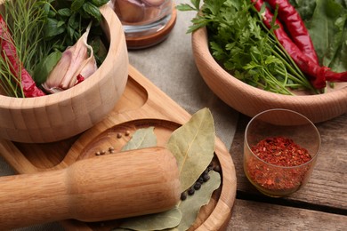 Photo of Mortar with pestle and different ingredients on wooden table, closeup