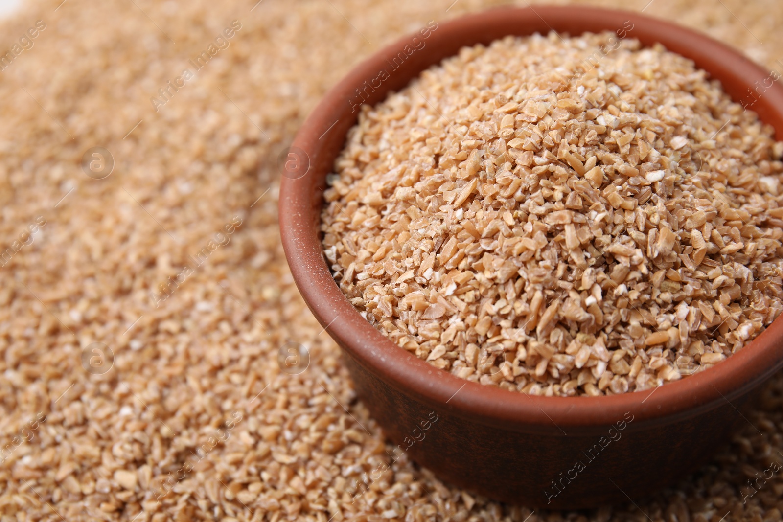 Photo of Bowl and dry wheat groats, closeup. Space for text