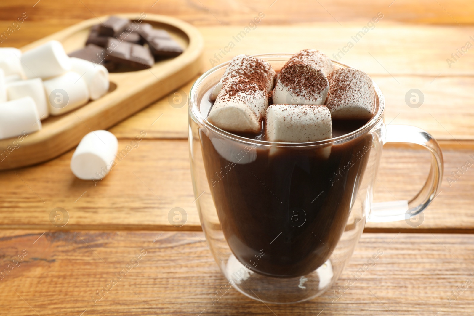 Photo of Cup of aromatic hot chocolate with marshmallows and cocoa powder on wooden table, closeup