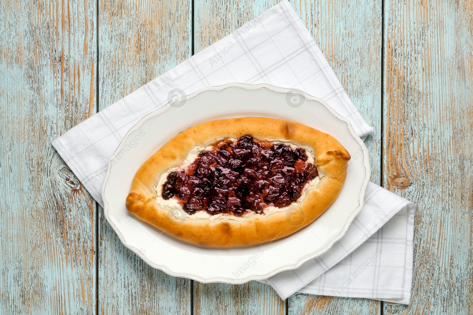 Photo of Delicious sweet cottage cheese pastry with cherry jam on light blue wooden table, top view