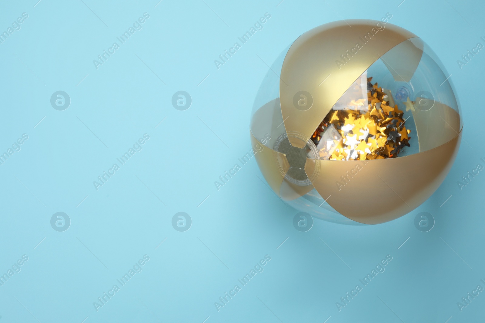 Photo of Bright beach ball on light blue background, top view. Space for text