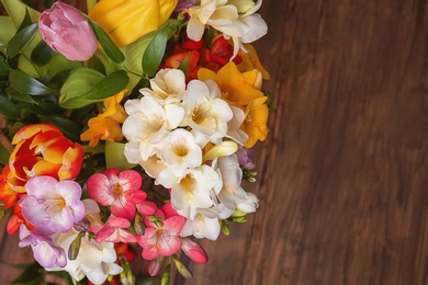 Photo of Beautiful freesia flowers on wooden table, top view