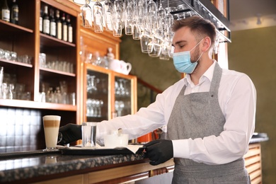 Photo of Waiter serving beverages in restaurant. Catering during coronavirus quarantine