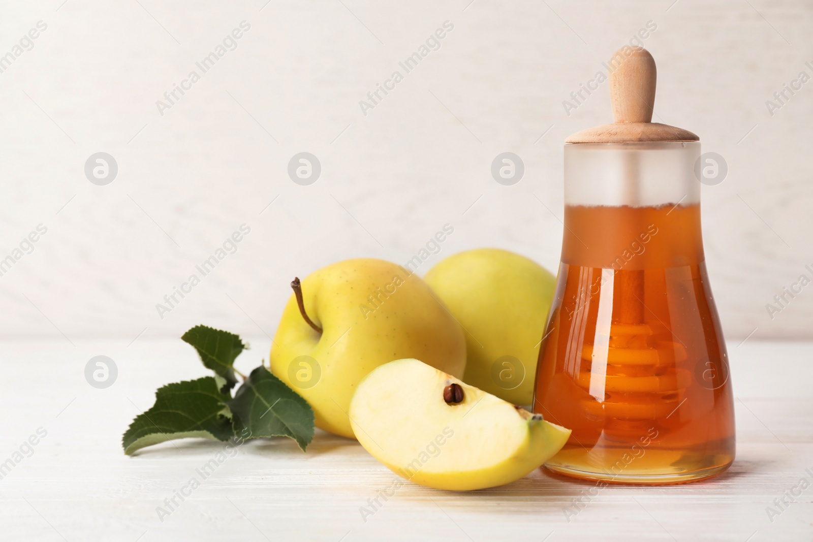 Photo of Jar of honey, apples and dipper on wooden table