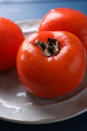 Photo of Delicious ripe persimmons on ceramic plate, closeup