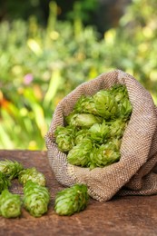 Sack and fresh hops on wooden table outdoors