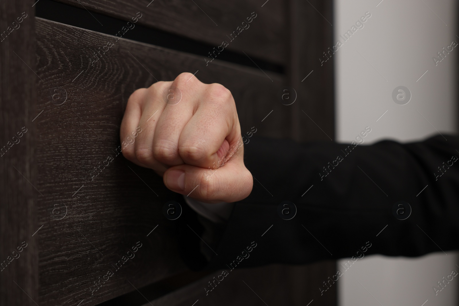 Photo of Collector knocking on door indoors, closeup view