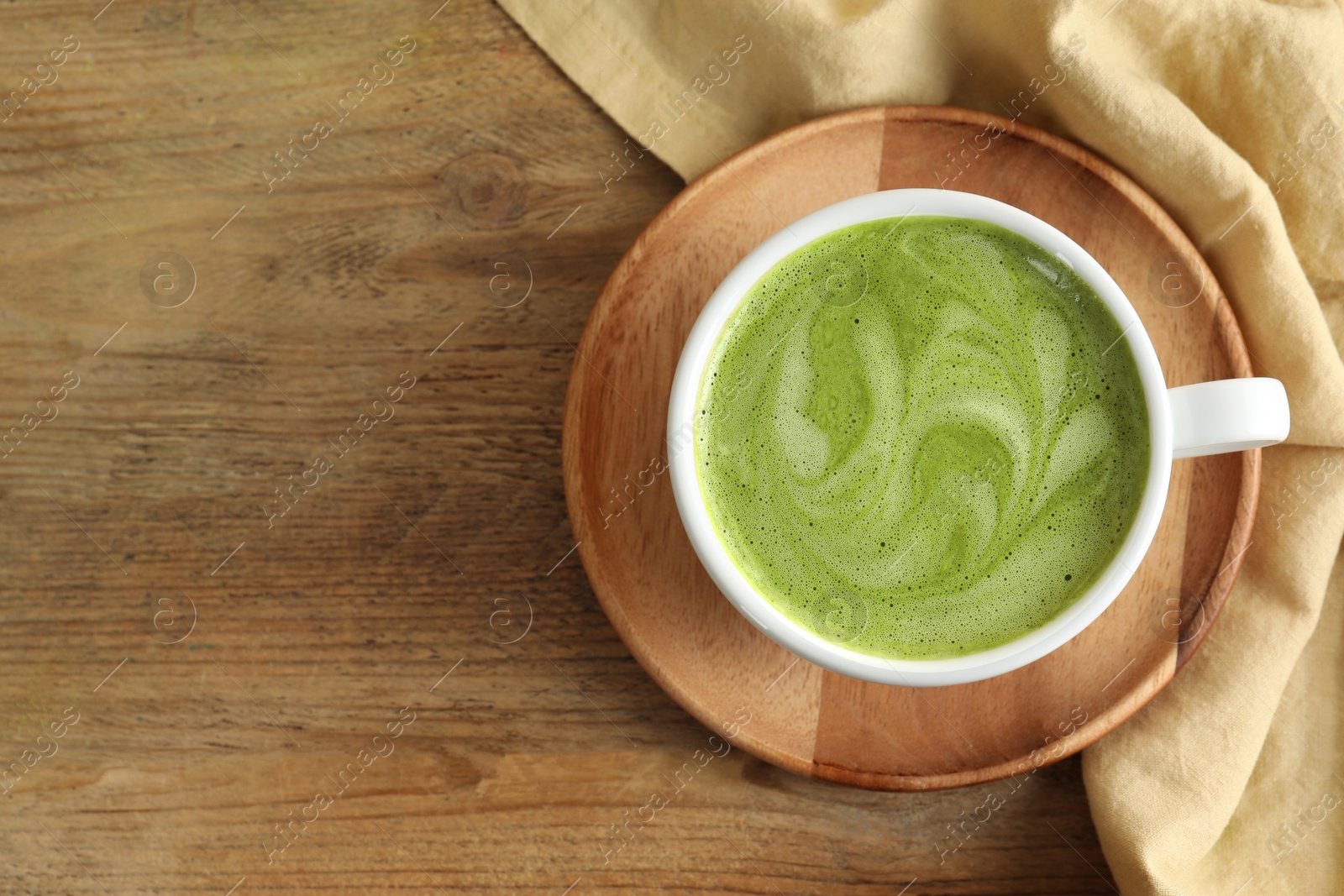Photo of Cup of aromatic matcha latte on wooden table, top view. Space for text