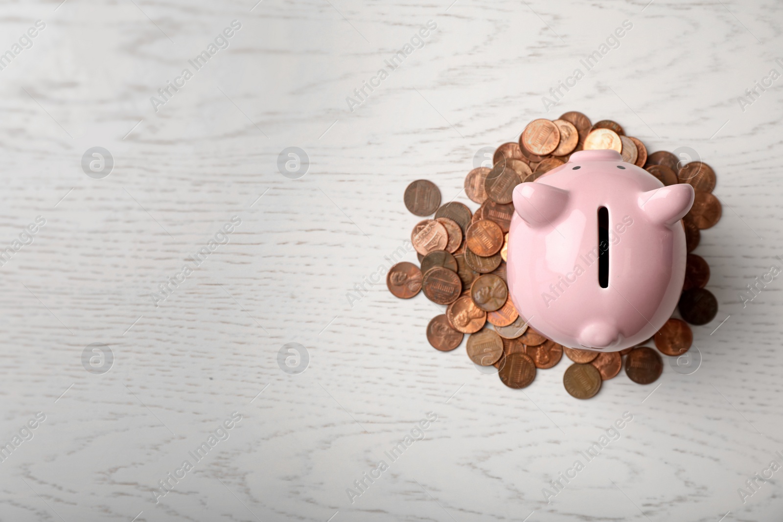 Photo of Cute piggy bank and coins on wooden background, top view with space for text
