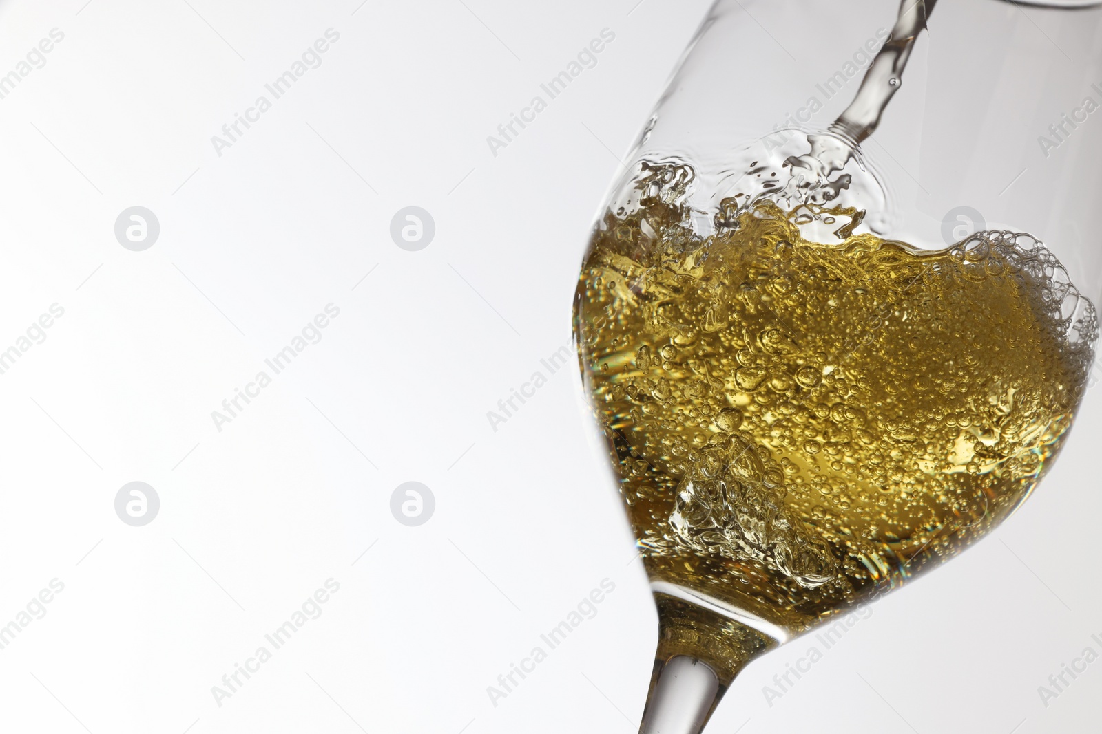 Photo of Pouring tasty aromatic wine in glass on white background, closeup. Space for text