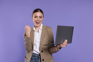 Happy woman with laptop on violet background