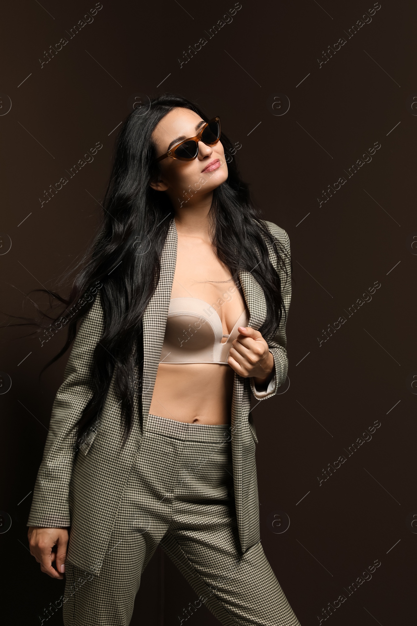 Photo of Beautiful woman with sunglasses in formal suit on dark brown background