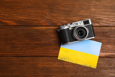 Photo of Vintage photo camera and beautiful printed picture on wooden table, flat lay with space for text. Creative hobby