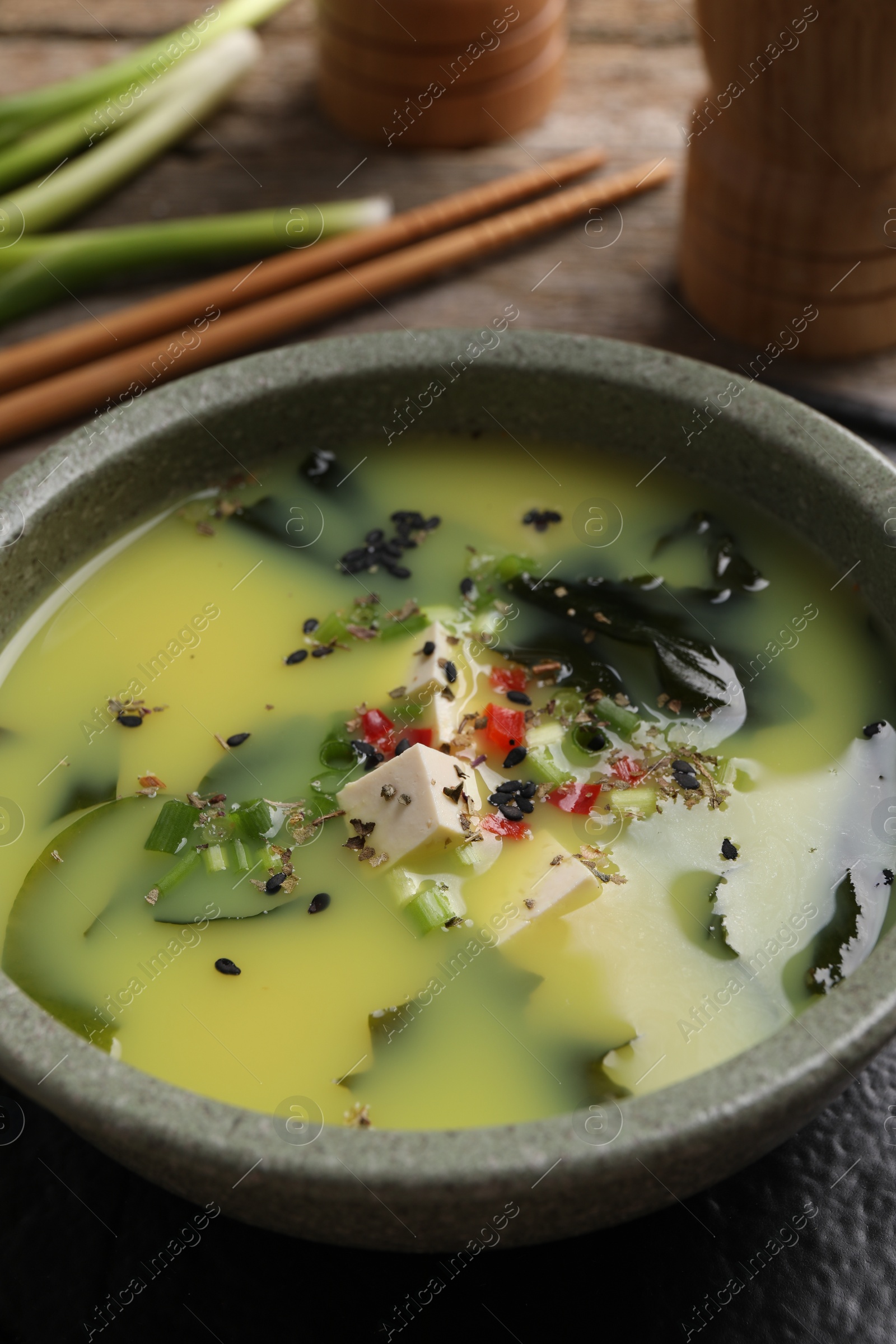 Photo of Bowl of delicious miso soup with tofu on table, closeup