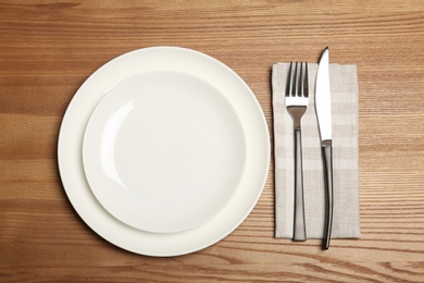 Photo of Empty dishware and cutlery on wooden background, top view. Table setting