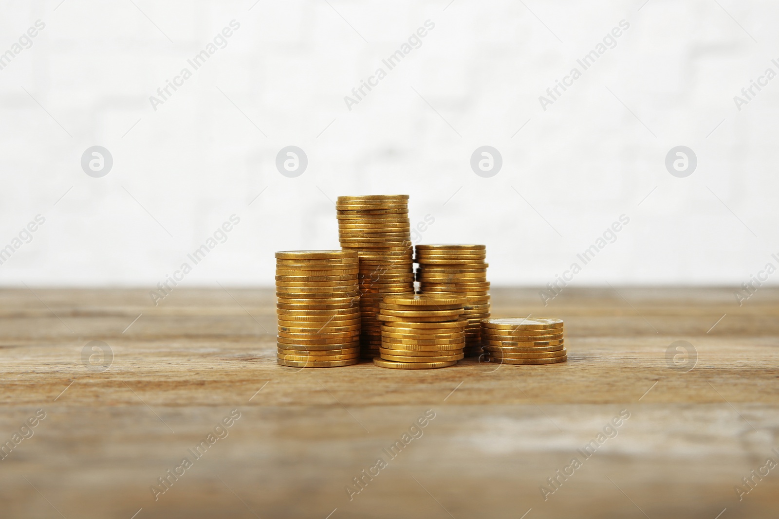 Photo of Many stacks of coins on table against light background