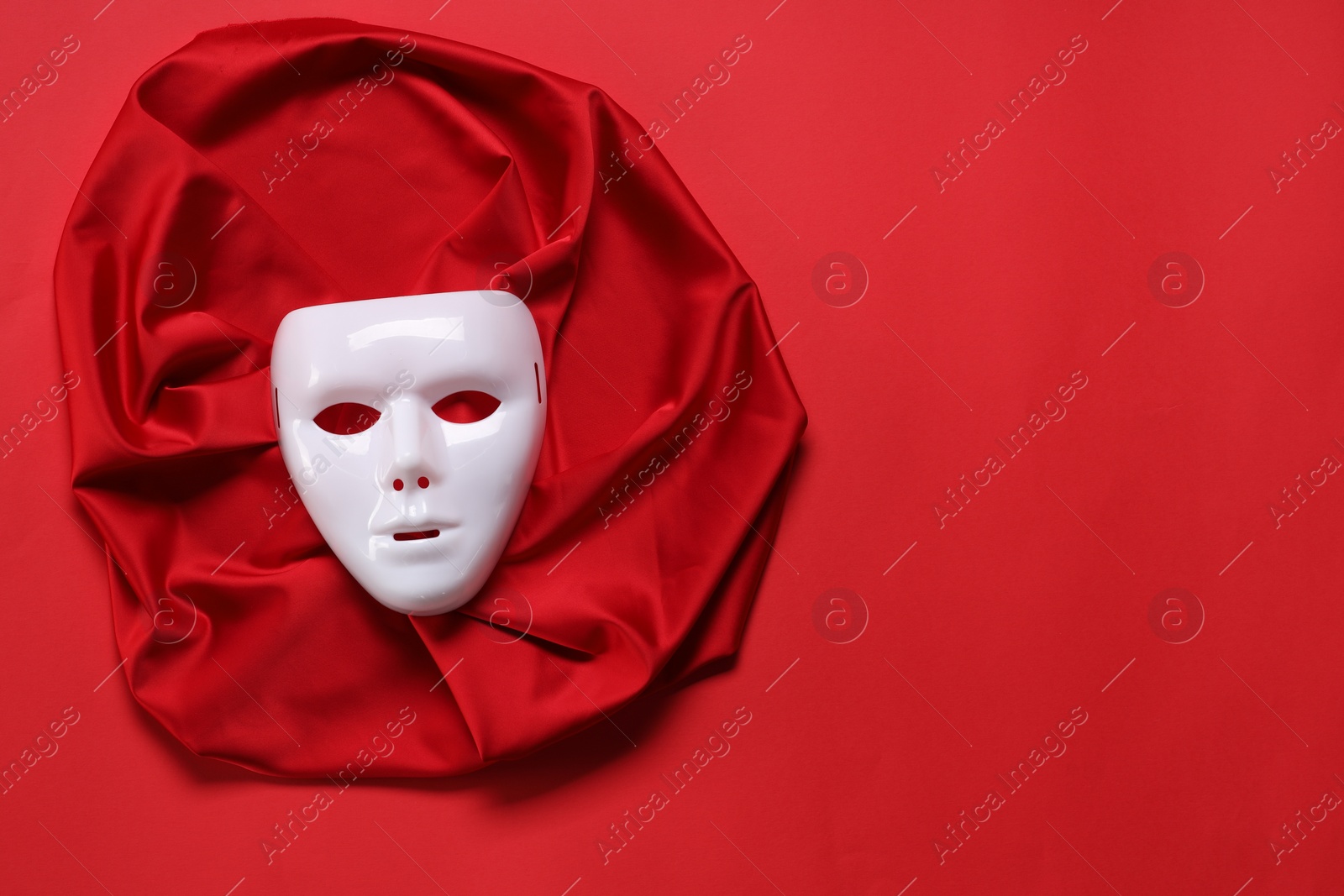 Photo of Theater arts. White mask and fabric on red background, top view. Space for text