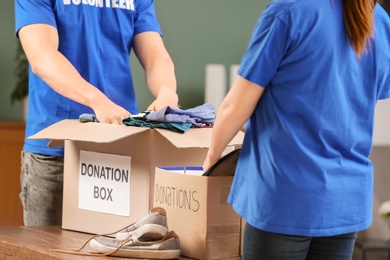 Photo of Volunteers putting clothes and shoes in donation boxes indoors