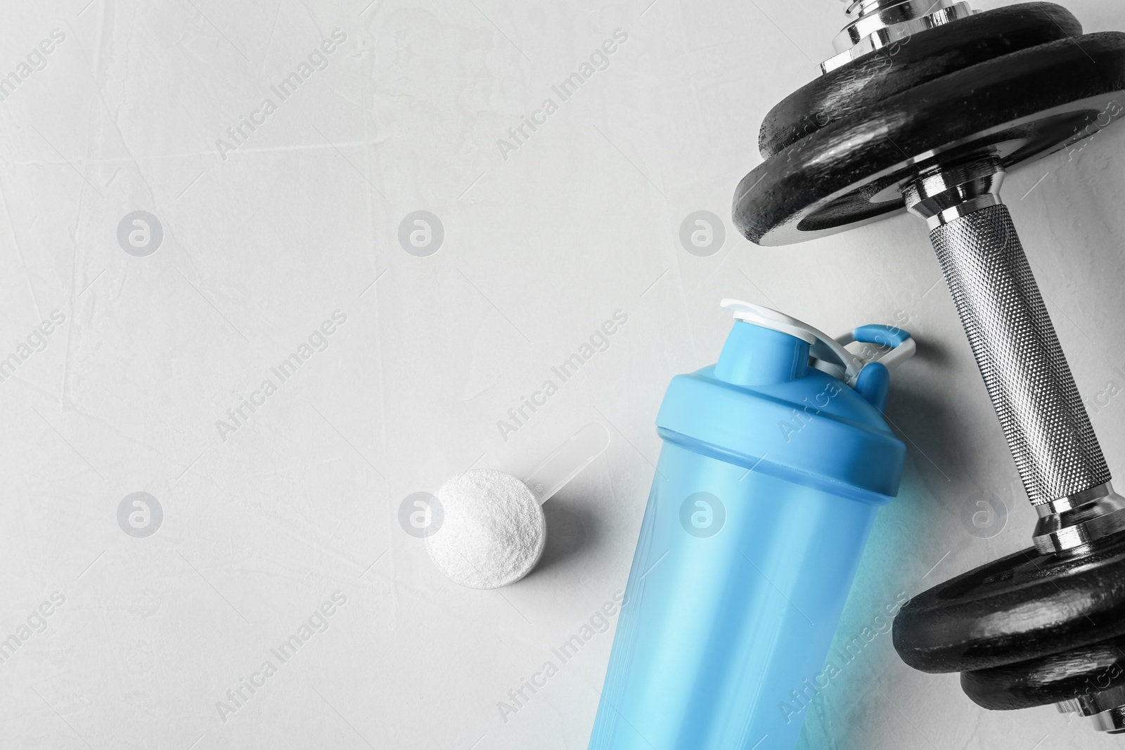 Photo of Flat lay composition with empty protein shake sport bottle and powder on table. Space for text