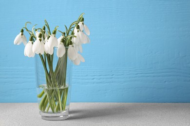 Photo of Beautiful snowdrops in vase on light grey table, space for text