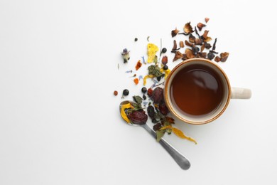 Cup of freshly brewed tea, dried herbs and spoon on white background, flat lay