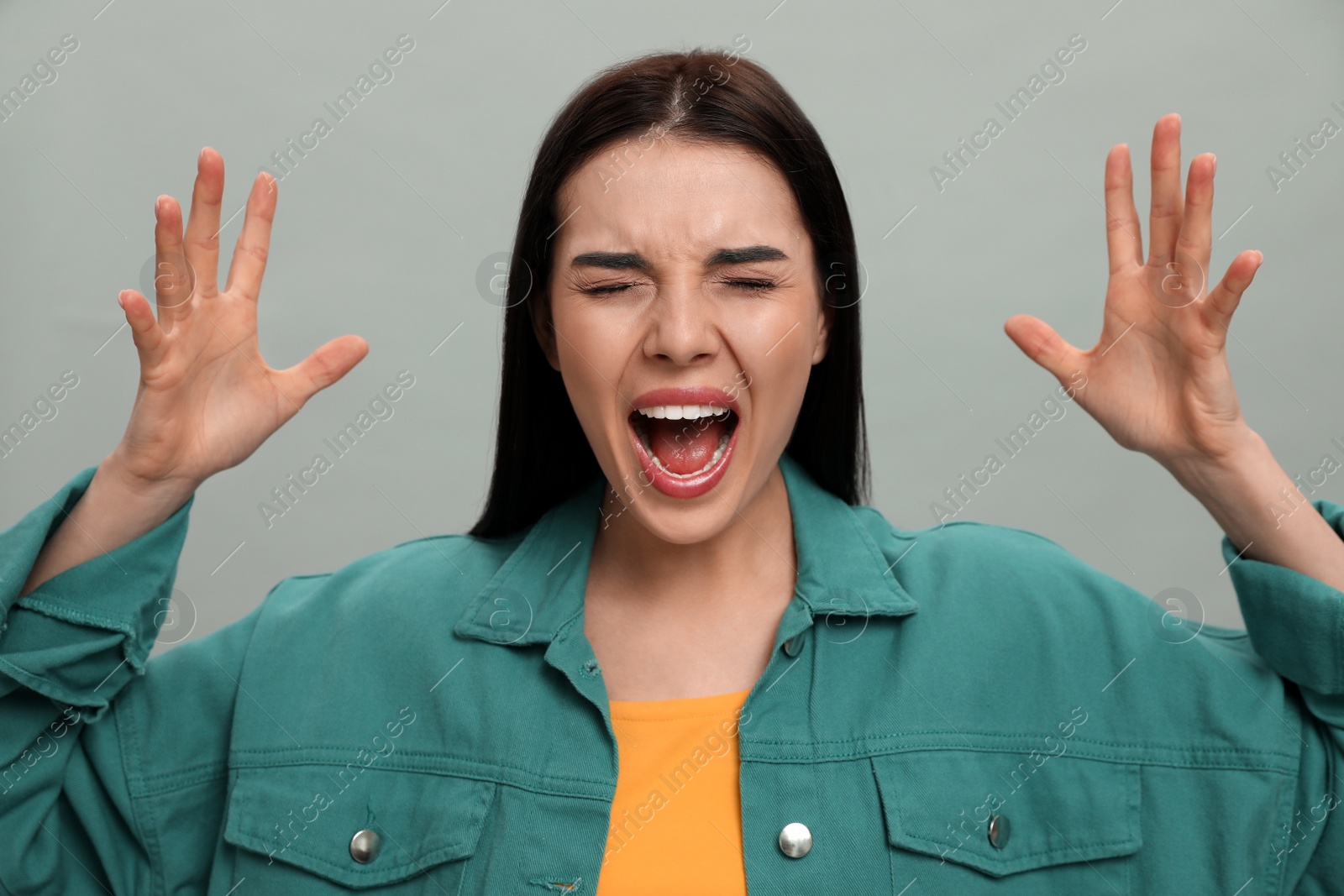 Photo of Angry young woman on grey background. Hate concept