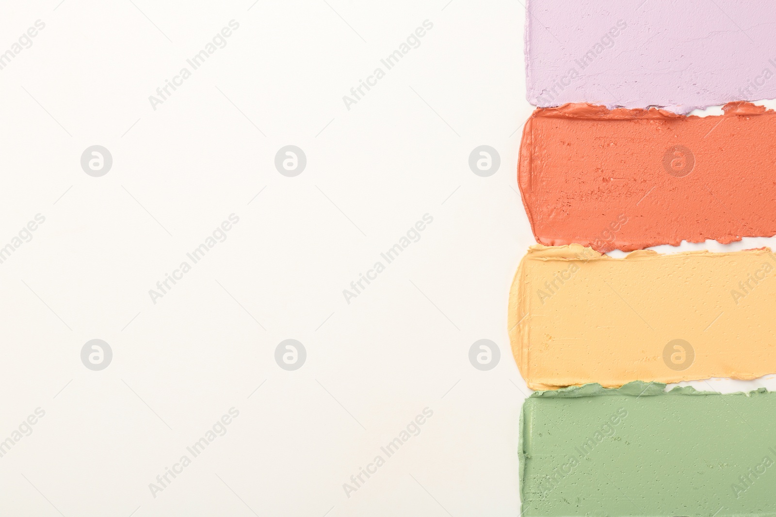 Photo of Samples of different color correcting concealers on white background, top view