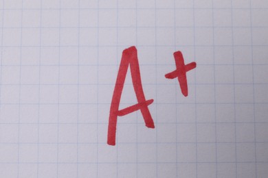 School grade. Red letter A with plus symbol on notebook paper, top view