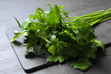 Photo of Bunch of fresh green parsley on grey table, closeup