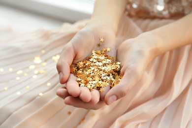 Photo of Woman holding confetti stars, closeup. Christmas celebration