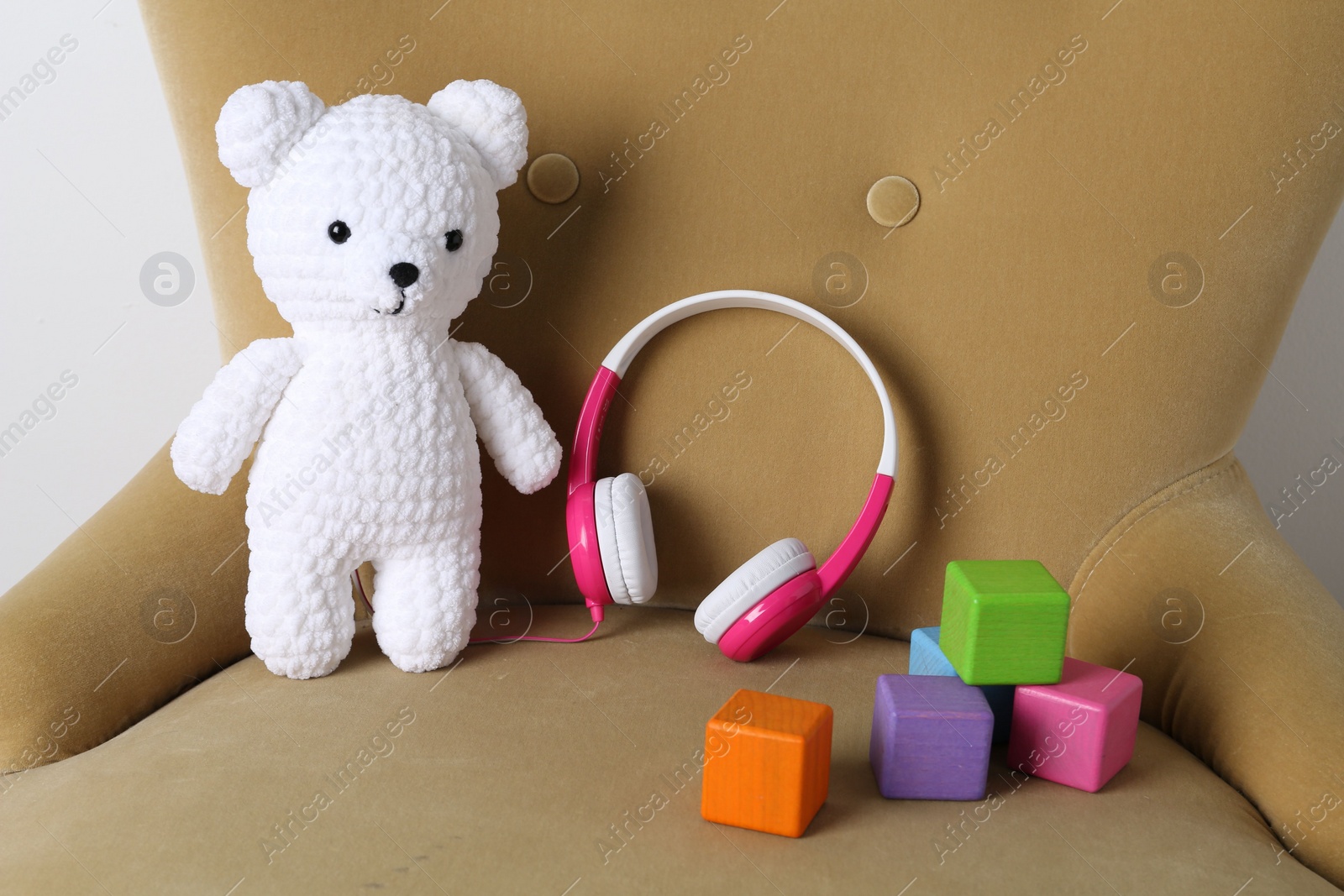 Photo of Baby songs. Toy bear, headphones and cubes on armchair