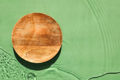 Photo of Presentation of product. Wooden podium in water on green background, top view. Space for text