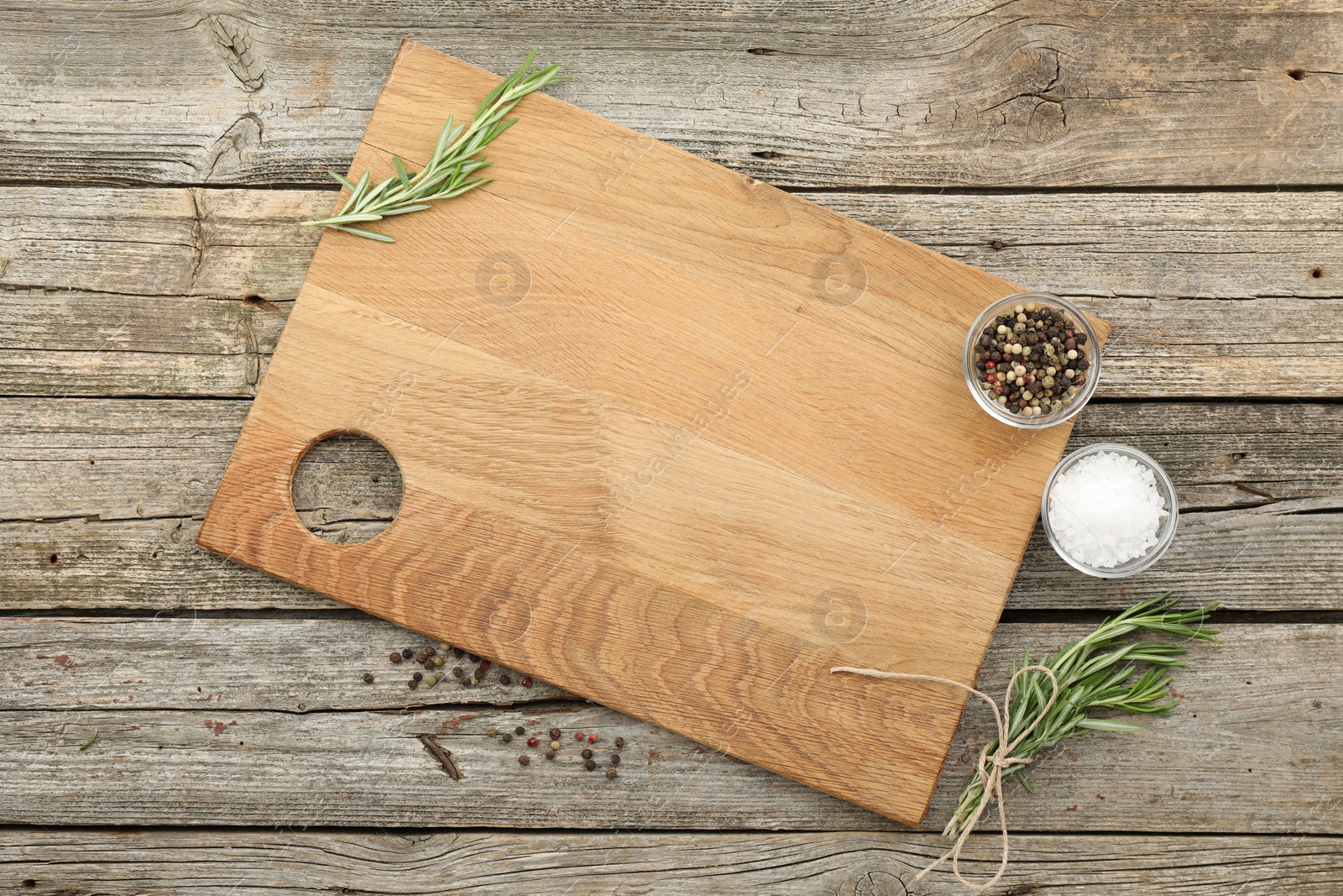 Photo of Cutting board, rosemary, salt and pepper on wooden table, flat lay. Space for text