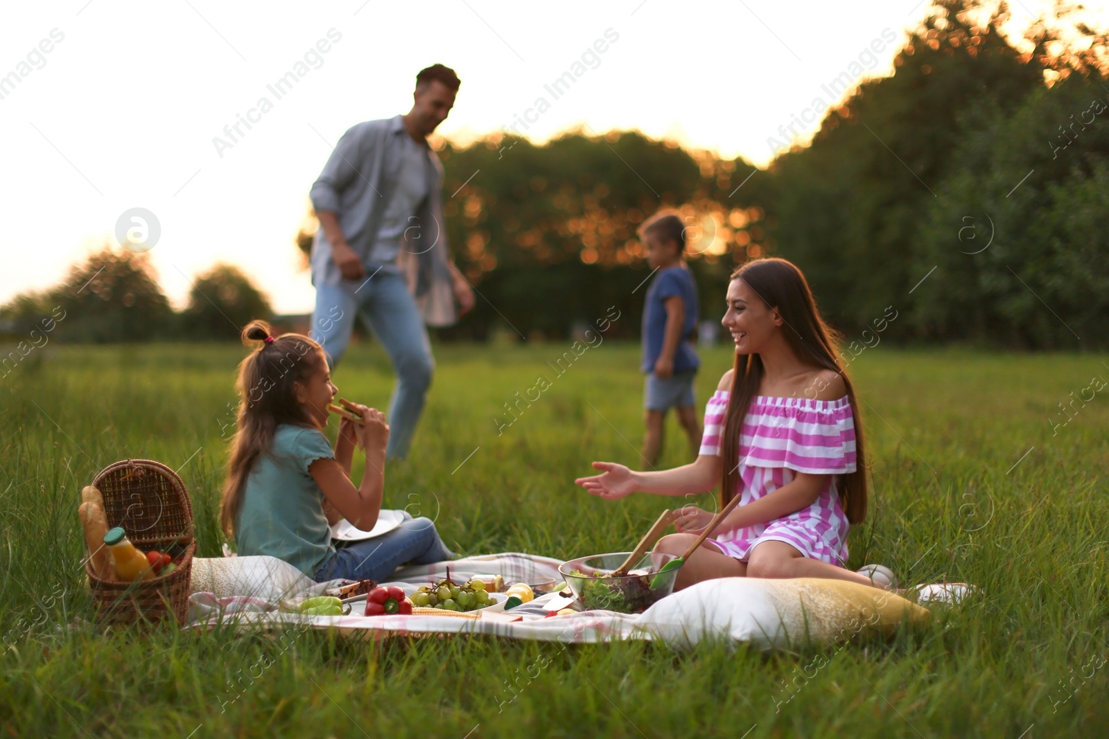 Photo of Happy family having picnic in park at sunset