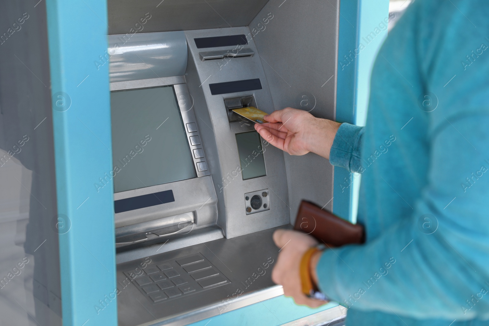 Photo of Young man using modern cash machine outdoors, closeup