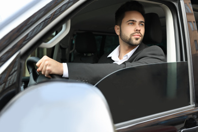 Handsome young man driving his modern car