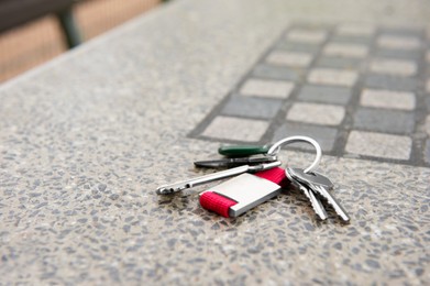 Photo of Keys forgotten on grey stone table outdoors. Space for text. Lost and found
