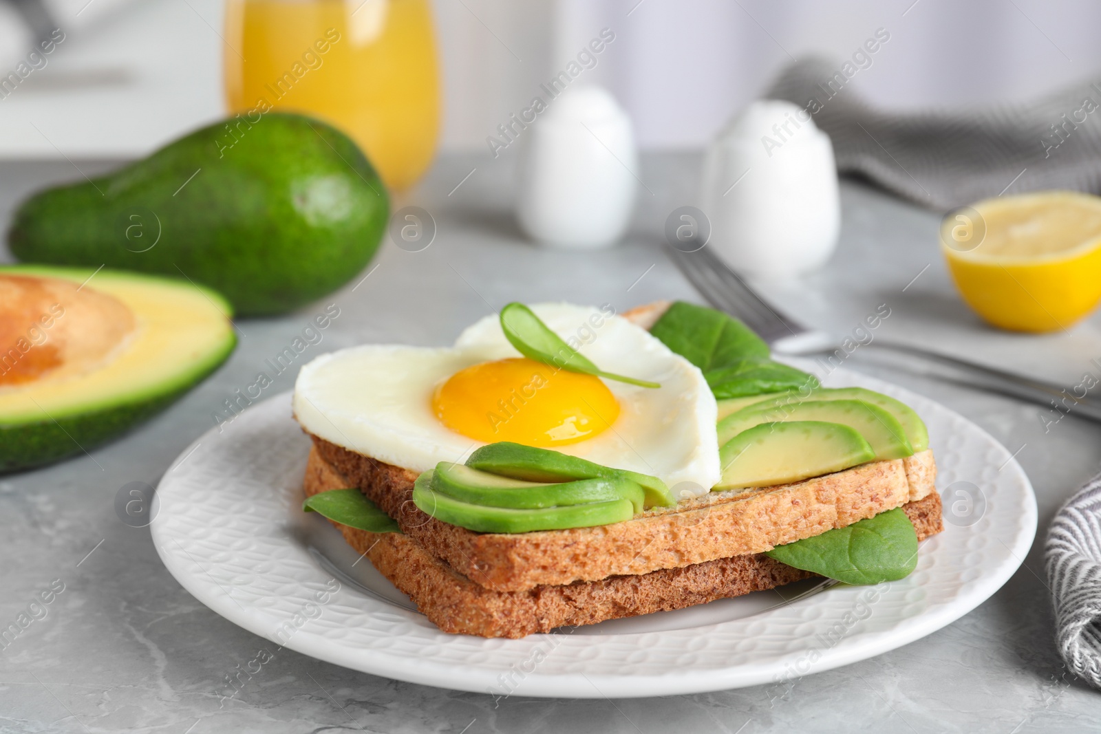 Photo of Tasty breakfast with heart shaped fried egg served on  grey table