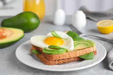 Photo of Tasty breakfast with heart shaped fried egg served on  grey table