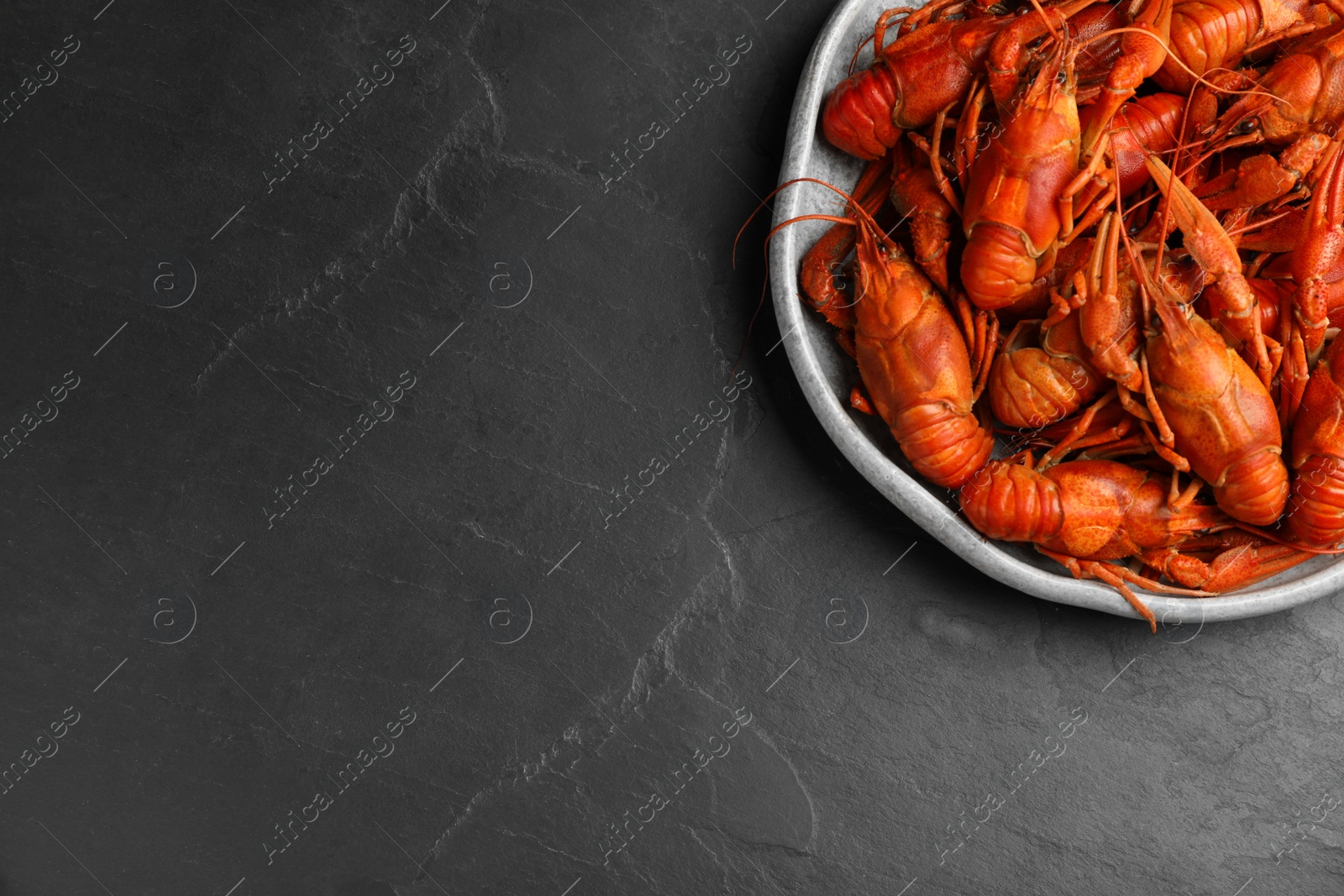 Photo of Delicious boiled crayfishes on black table, top view. Space for text