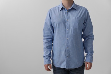 Man wearing light blue shirt on white background, closeup