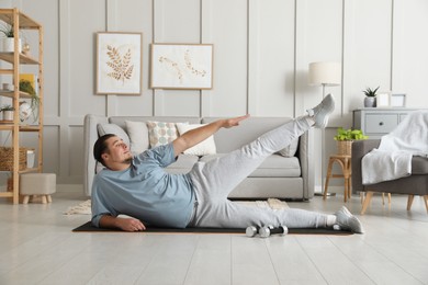 Photo of Overweight man doing exercise on mat at home