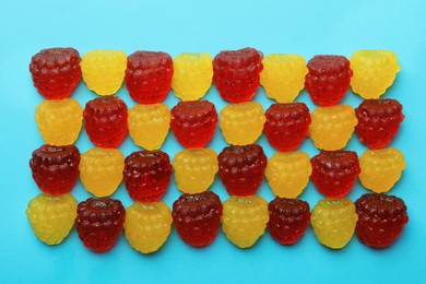 Photo of Delicious gummy raspberry candies on light blue background, flat lay
