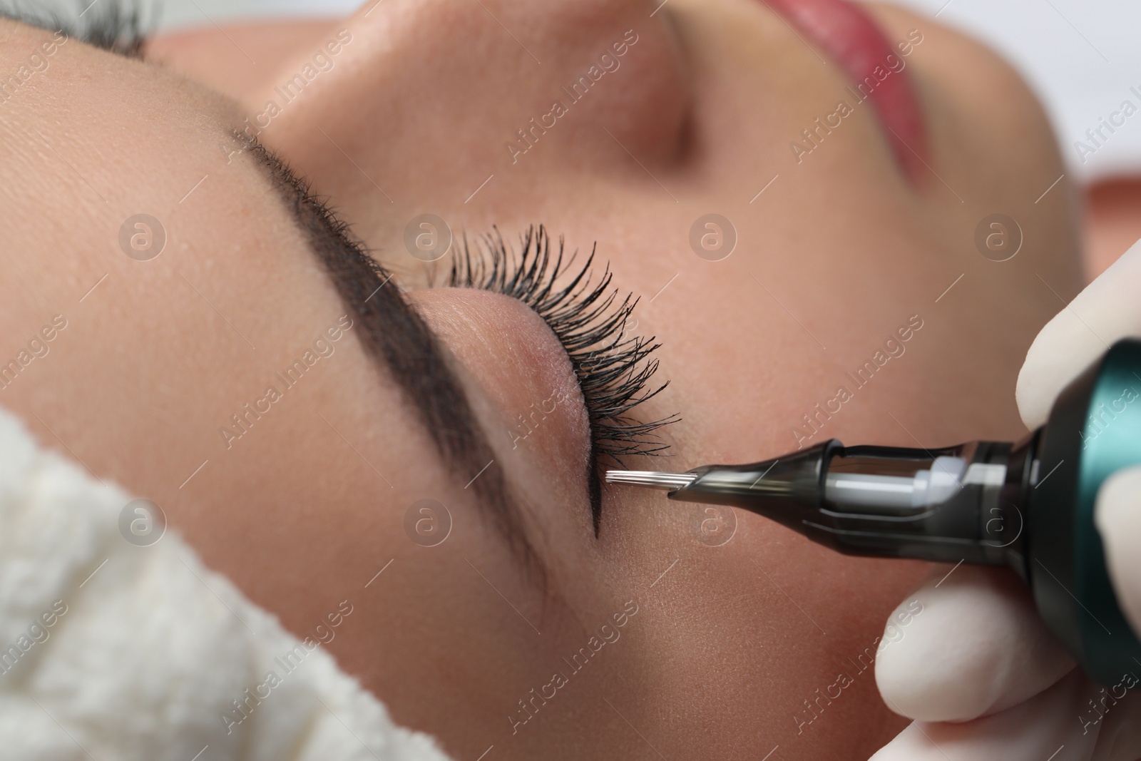 Photo of Young woman undergoing procedure of permanent eye makeup, closeup