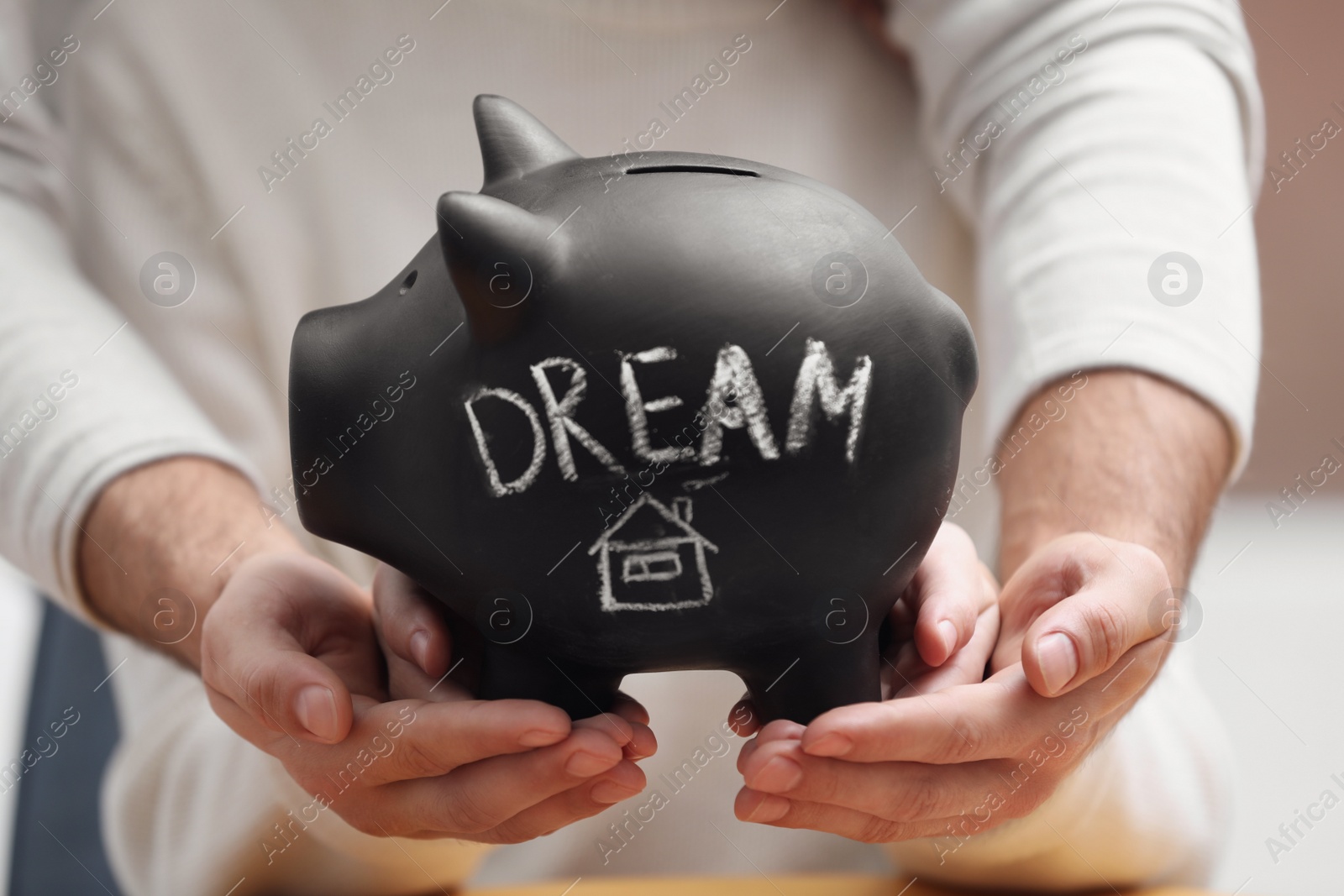 Photo of Couple holding piggy bank with word DREAM, closeup