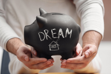 Couple holding piggy bank with word DREAM, closeup