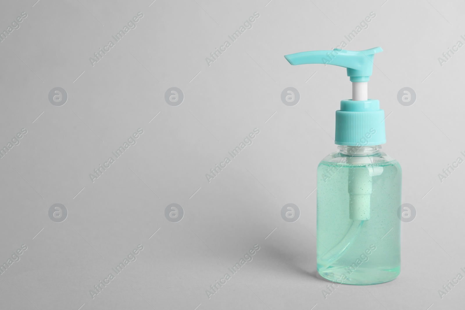 Photo of Dispenser bottle with antiseptic gel on light grey background. Space for text